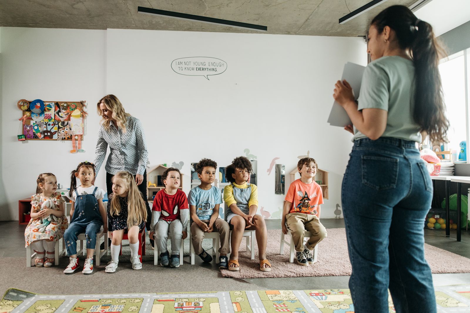 Preschool children and their teachers enjoying an activity together in a bright classroom